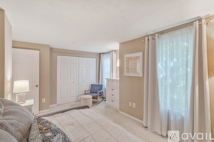 A bedroom with a large bed and a window with curtains.