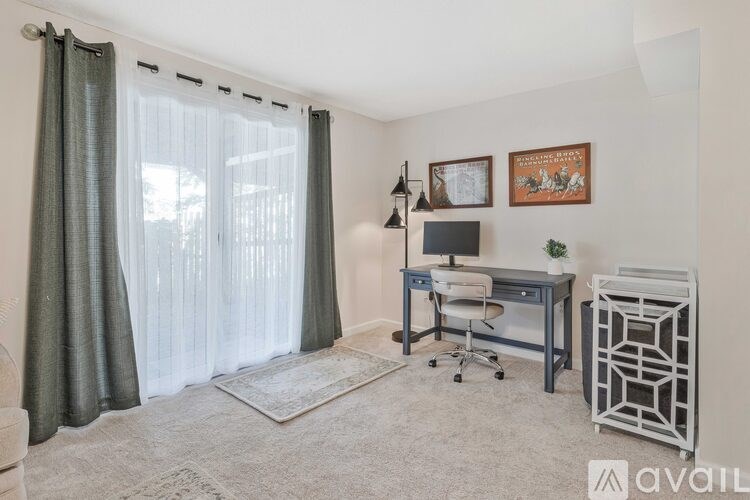 A room with a desk, chair, and a window with curtains.