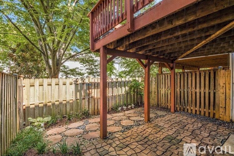A wooden deck with a red railing and a stone pathway.