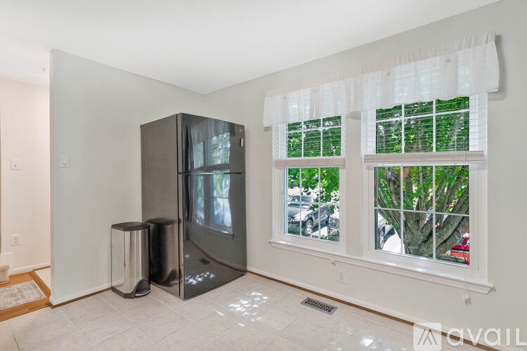 A kitchen with a black fridge and a window with a view of trees.