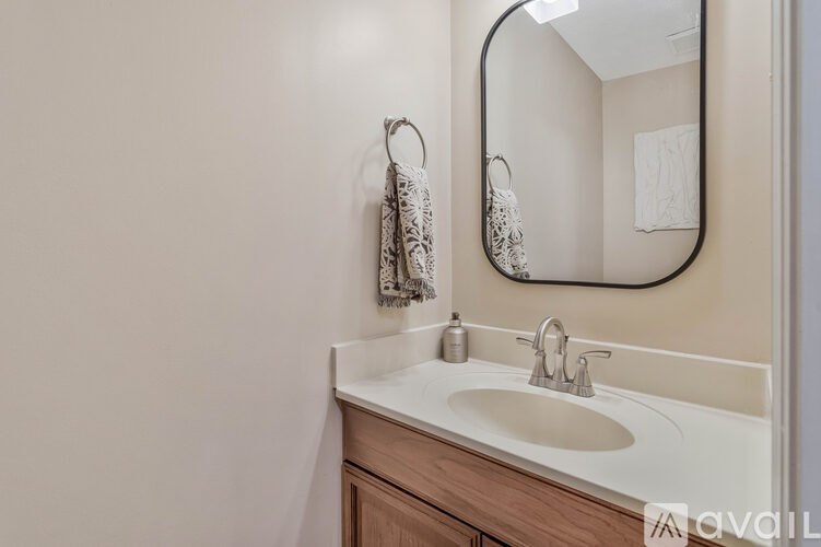 A bathroom with a sink, mirror, and towel rack.