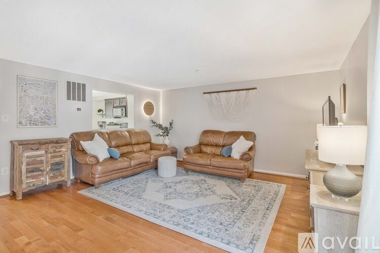 A living room with two brown leather couches, a white side table, and a rug.