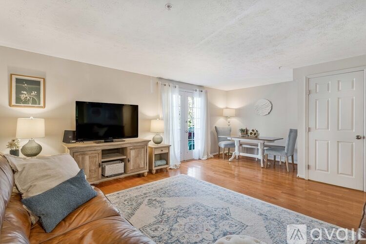 A living room with a brown leather couch and a television on a cabinet.