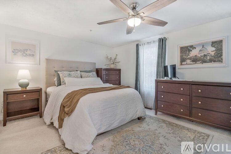 A bedroom with a large bed, a ceiling fan, and a dresser.