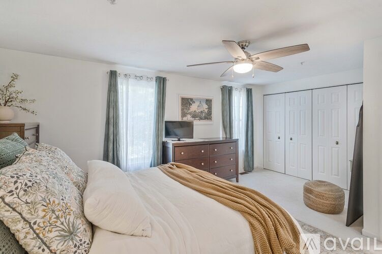 A bedroom with a large bed and a ceiling fan.