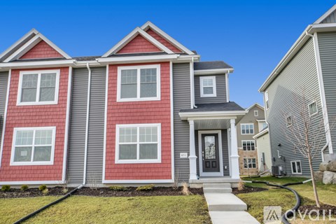 A red and grey house with a front porch and a clear blue sky.