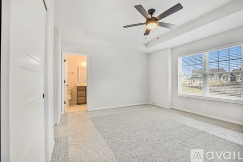 A spacious room with a ceiling fan and a carpeted floor.