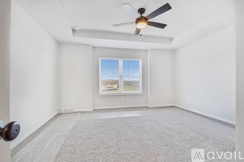 A room with a ceiling fan and a window with blinds.