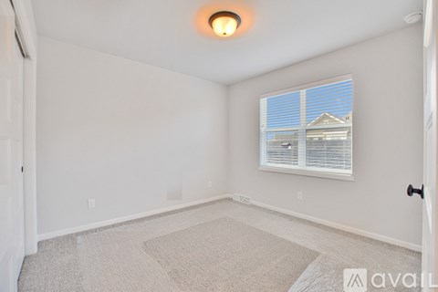 A room with a carpeted floor and a window with blinds.