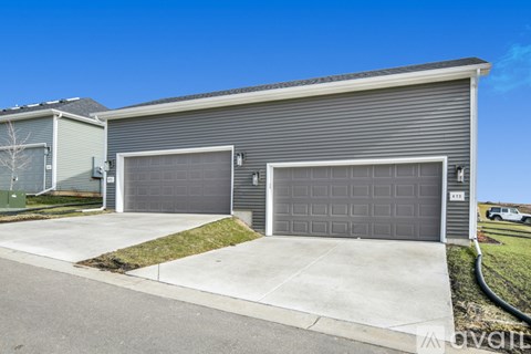 A grey two-car garage with a white door is attached to a house.