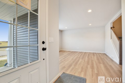 A room with wooden flooring and a white door with a window on the side.