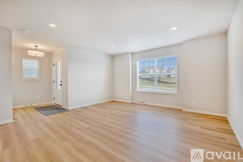 A spacious room with wooden flooring and a large window.