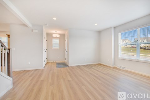 A spacious room with wooden flooring and a large window.