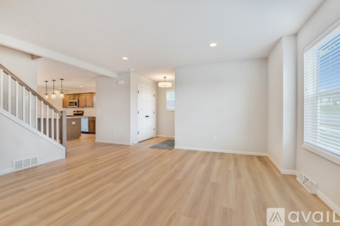 A spacious room with wooden flooring and white walls.