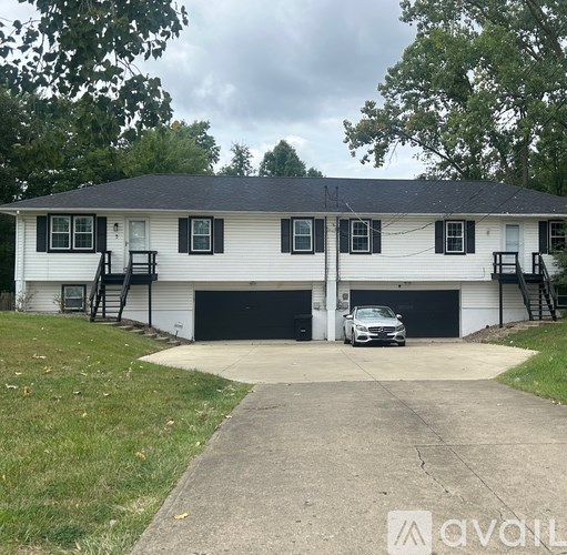 A two-car garage with a white house and black shutters.