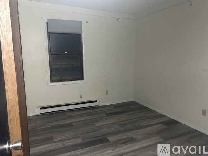 A room with a window and a wooden floor.