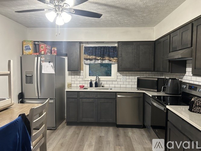 A kitchen with a refrigerator, sink, and stove.