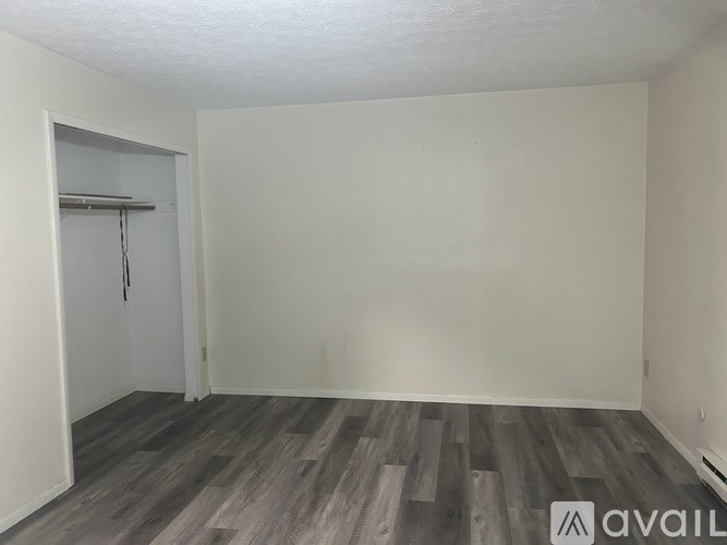 A room with a grey wooden floor and a white door.