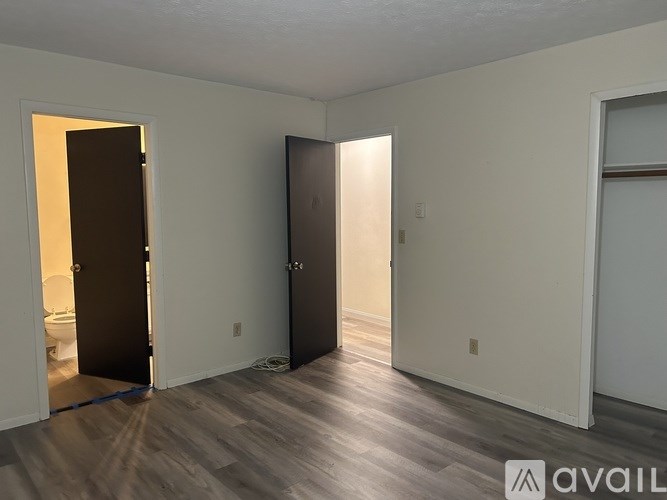 A room with a wooden floor and two doors, one of which is open.