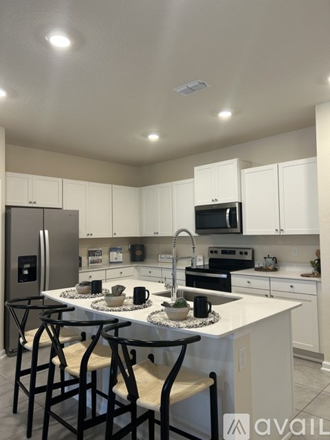 A kitchen with white cabinets and black countertops.