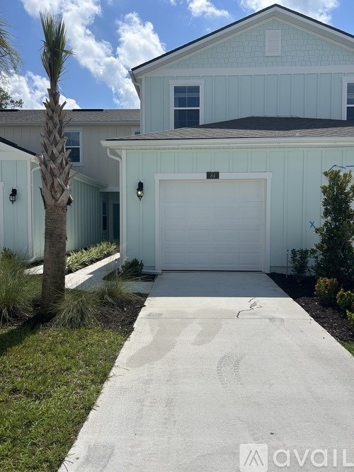 A house with a white garage door and a palm tree in front.
