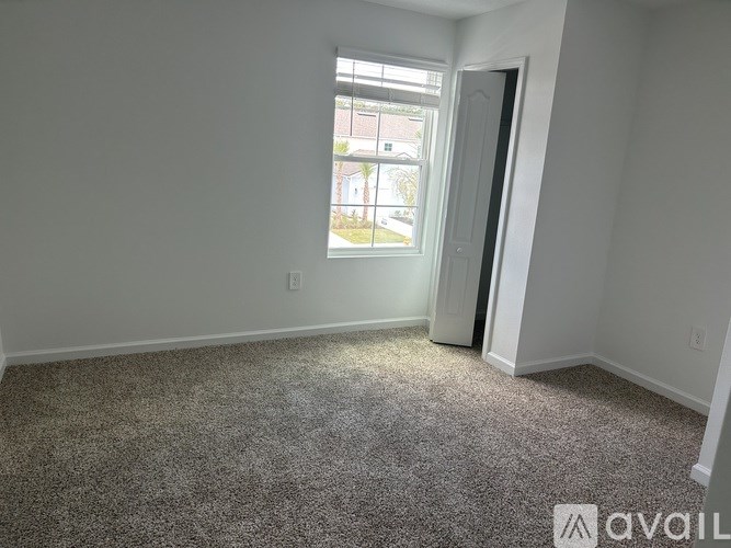 A carpeted room with a window and a door.