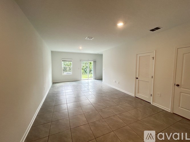 A spacious room with tiled flooring and two doors.