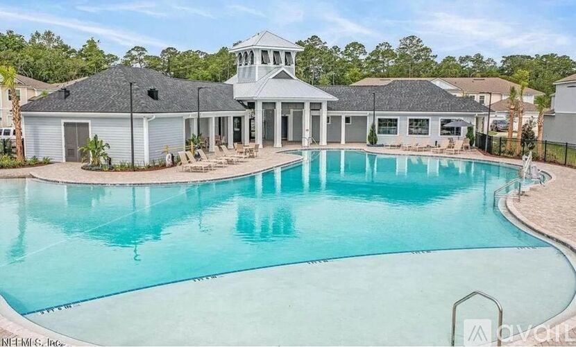 A large swimming pool in front of a house with a gazebo.