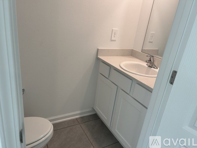 A bathroom with a toilet, sink and mirror.