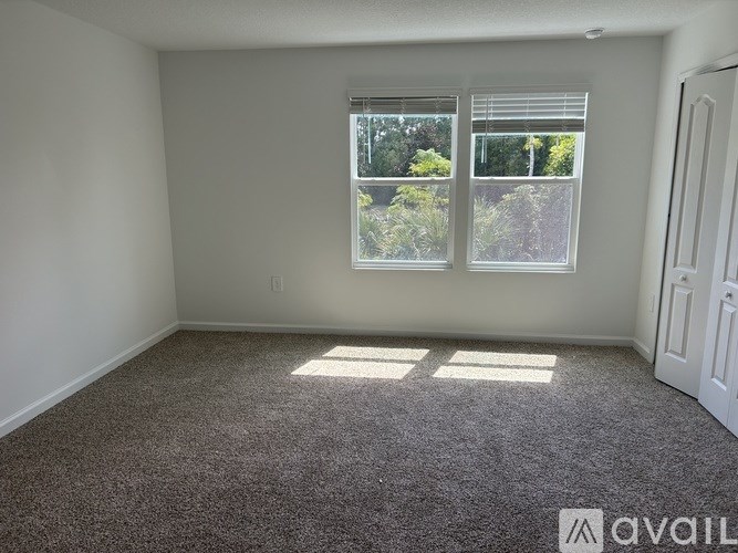 A room with a carpeted floor and a window with blinds.