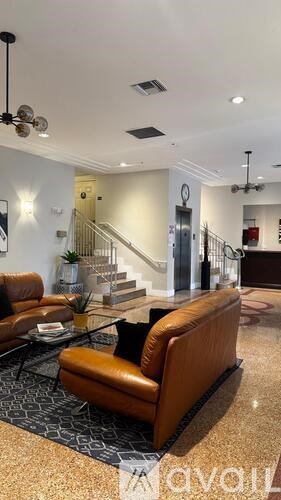 A living room with a brown leather couch and a glass coffee table.