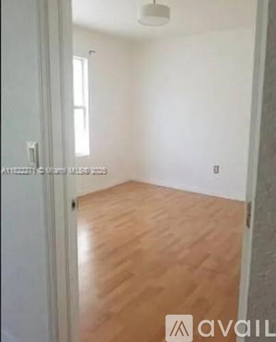 A room with wooden flooring and white walls.