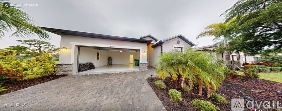 A house with a driveway and a garage is surrounded by greenery.