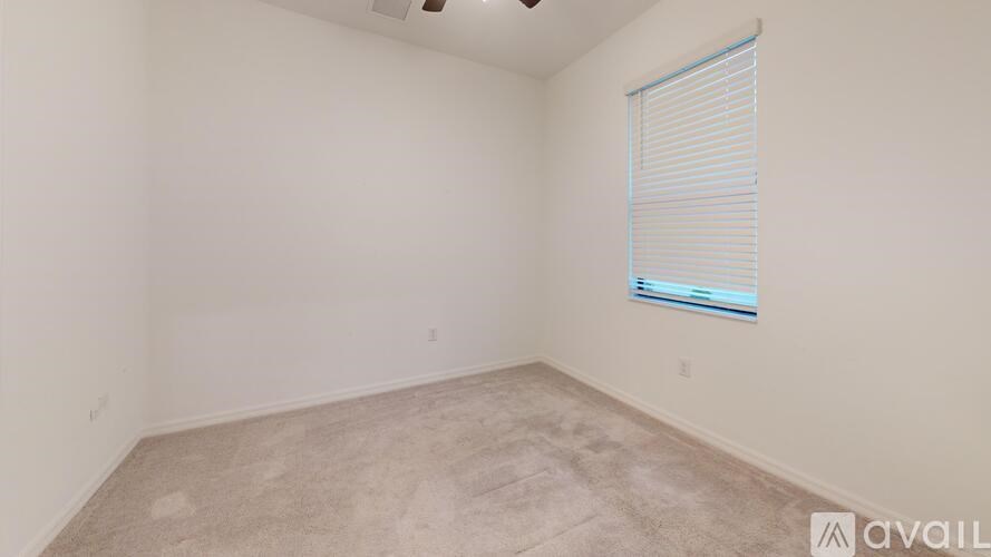 A room with a carpeted floor and a window with blinds.