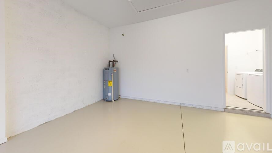 A room with a white wall and a grey floor with a white door on the right side.