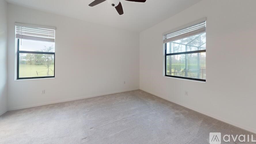 A room with a ceiling fan and two windows.