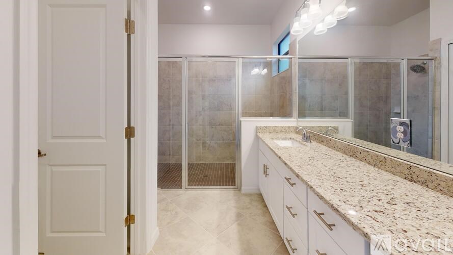 A bathroom with a marble countertop and a walk-in shower.