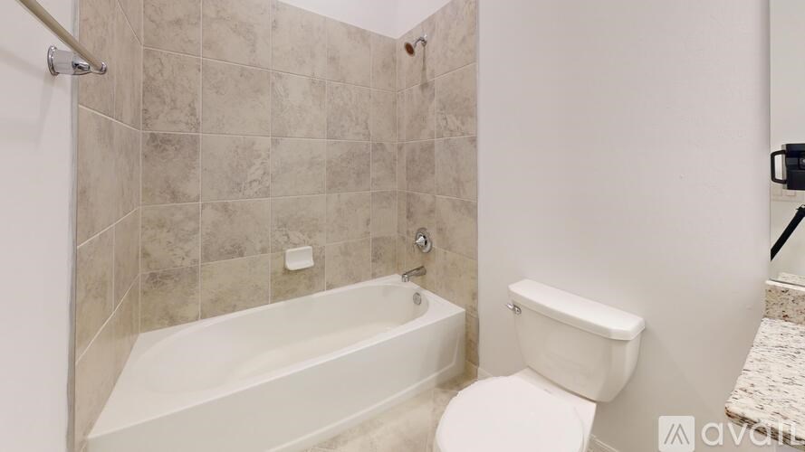 A bathroom with a white toilet and a bathtub with tiled walls.