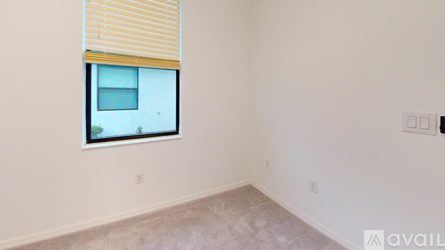 A room with a window covered by blinds and a wall with switches and sockets.