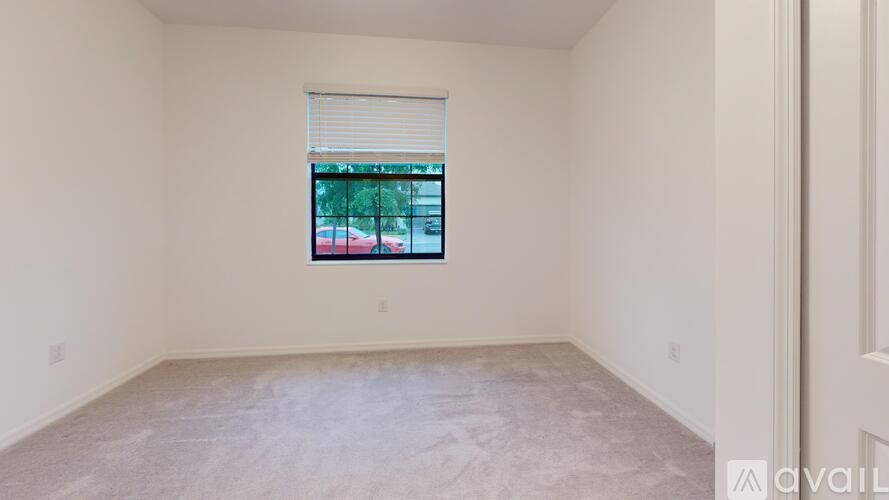 A room with a window showing a red car outside.