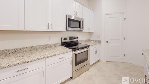 A kitchen with white cabinets and a granite countertop.
