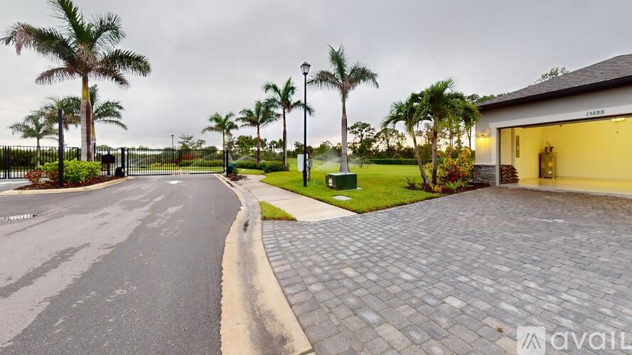 A street with palm trees and a house with a driveway.