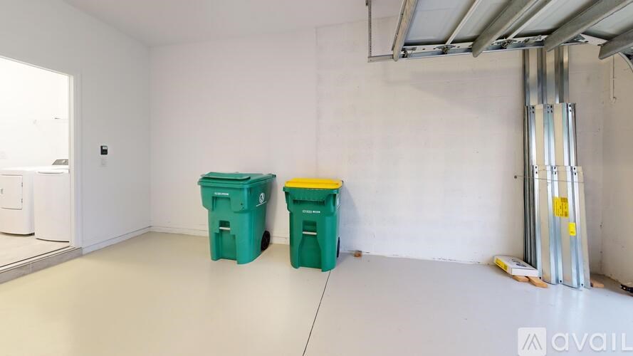 Two green bins are placed in a white room.