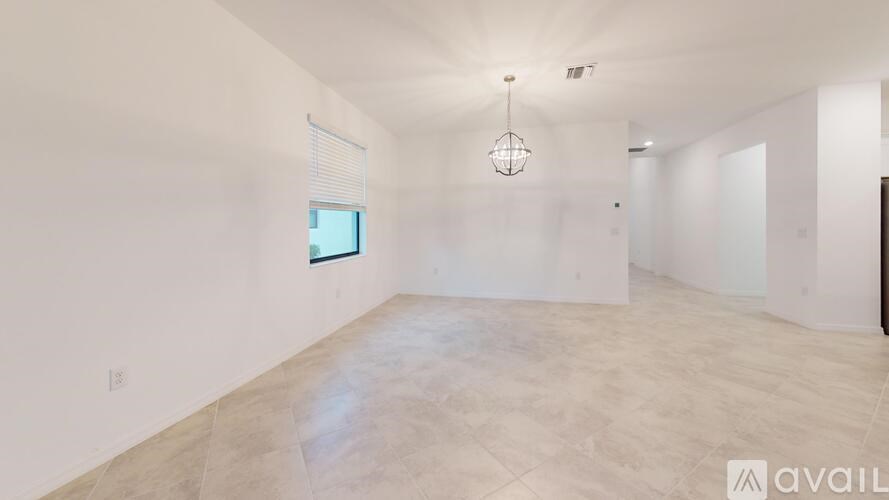 A spacious room with a large window and a hanging light fixture.