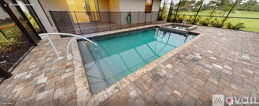 A pool with a brick patio and a metal railing.