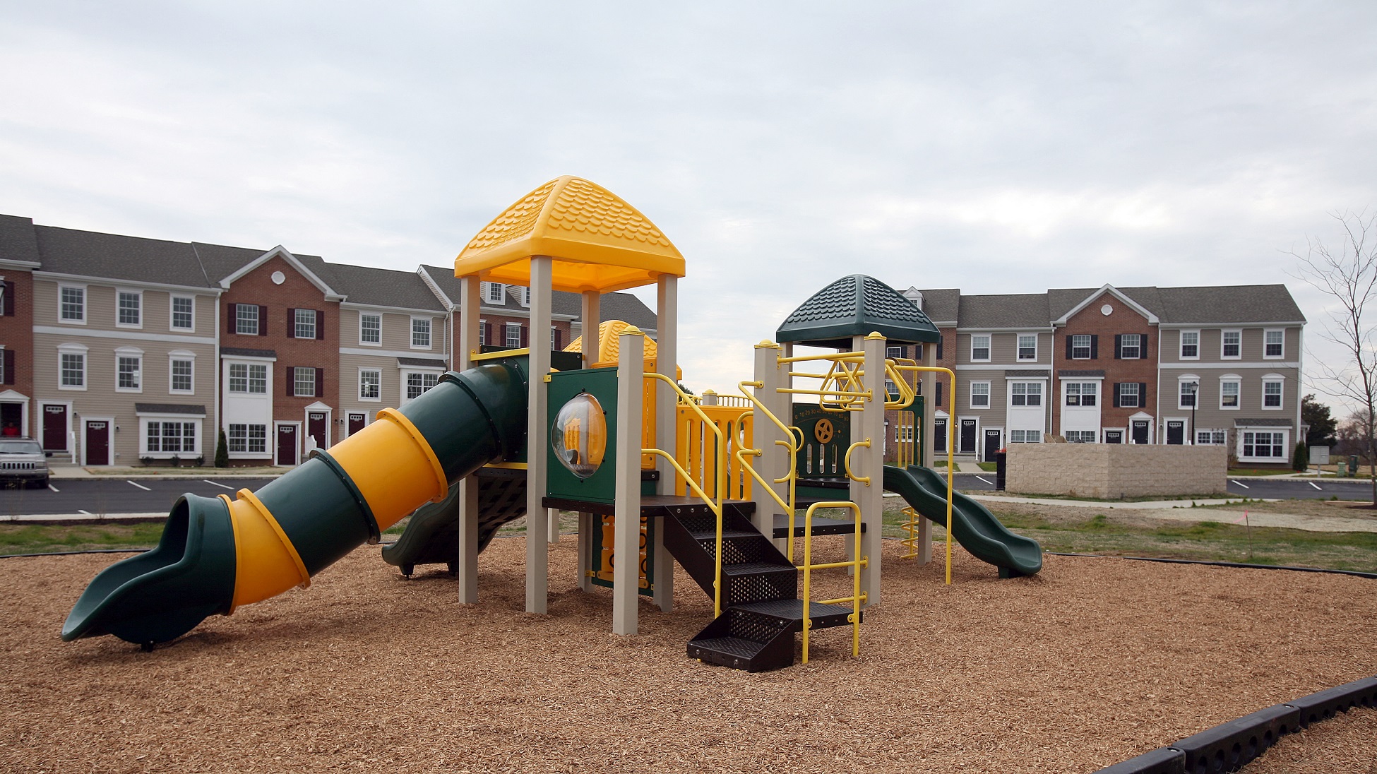 a playground with a slide and other playground equipment in front of apartments