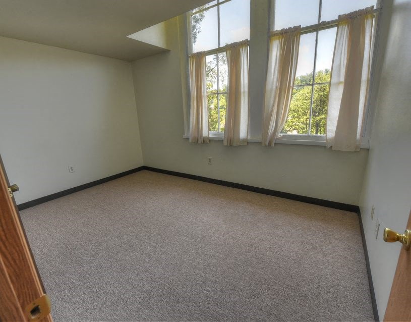 an empty room with a door and three windows