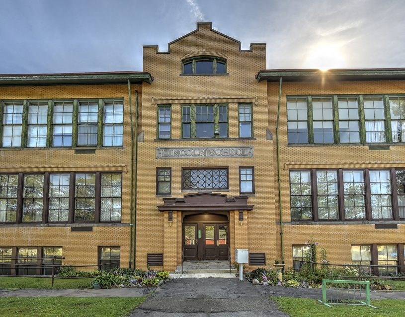 the front of a school building with the sun shining through the windows