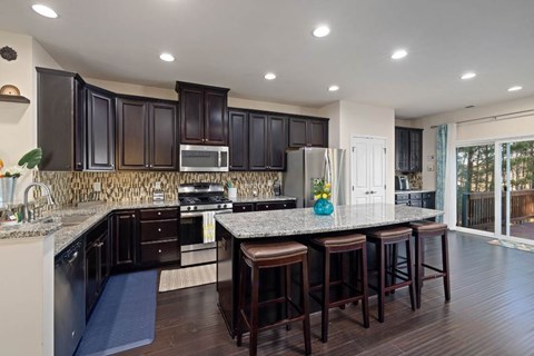A kitchen with dark brown cabinets and a granite countertop.