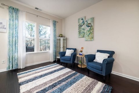 A living room with two blue chairs and a rug.